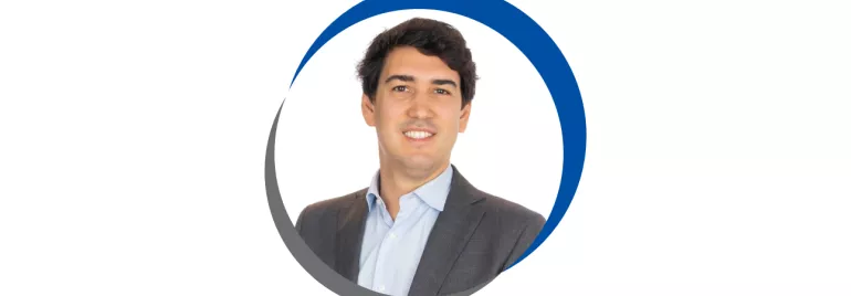 Homem em terno sorrindo, dentro de círculo azul e cinza.
