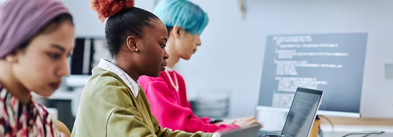 Pessoas concentradas em computadores em um ambiente de escritório.