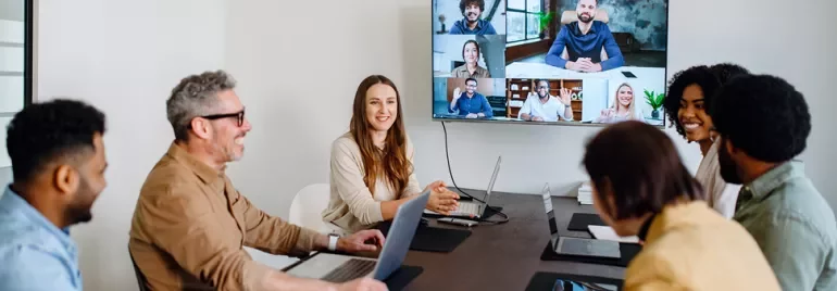 Uma equipa híbrida a trabalhar em conjunto numa reunião, utilizando competências de liderança para melhorar a produtividade dos colaboradores.