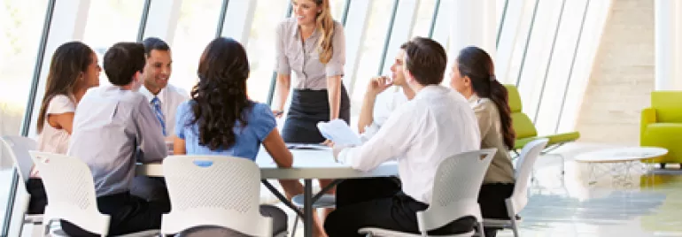 Equipe discutindo em reunião ao redor de mesa em escritório moderno.