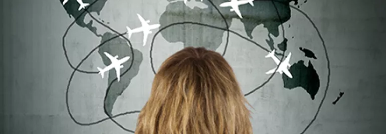 Pessoa olhando mapa do mundo com aviões desenhados.