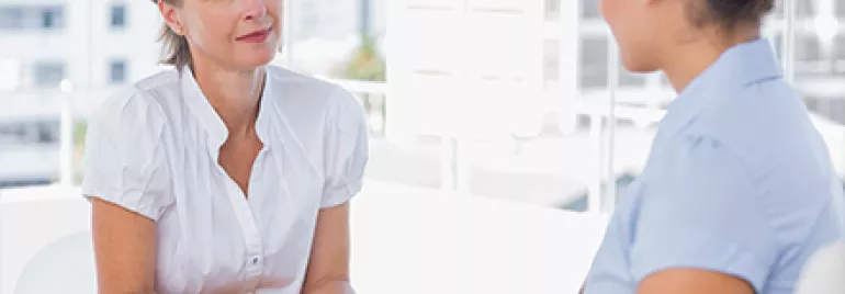 Duas mulheres conversando em uma mesa de escritório.
