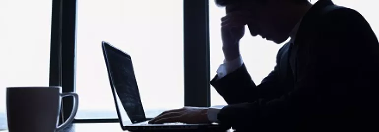 Homem preocupado no trabalho olhando para laptop.