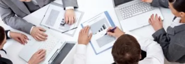 Reunião de negócios com pessoas trabalhando em laptops e gráficos.
