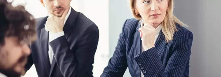 Pessoas em reunião de negócios, algumas olhando para o lado.