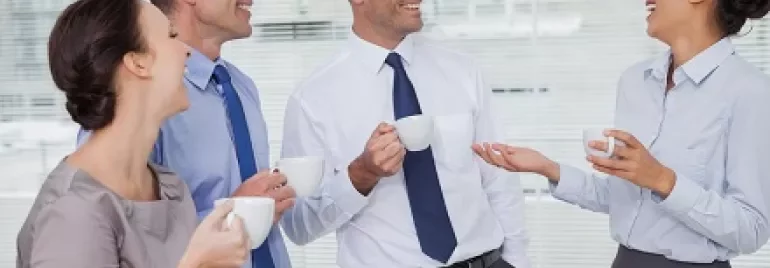Grupo de colegas conversando e sorrindo durante uma pausa para o café.
