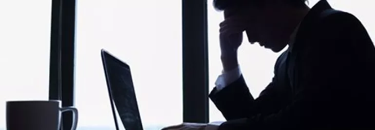Homem preocupado sentado em frente ao laptop.