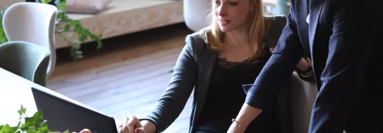 Duas mulheres discutindo um trabalho em frente a um laptop.