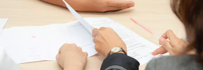 Pessoa analisando documentos em reunião de trabalho.