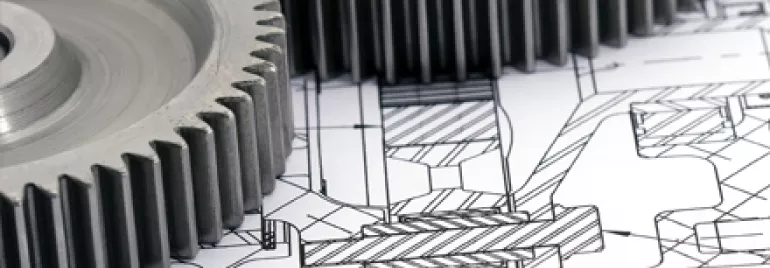 Engrenagens metálicas sobre um desenho técnico detalhado.