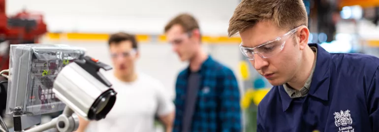 Homem de óculos de proteção trabalha em laboratório de engenharia.