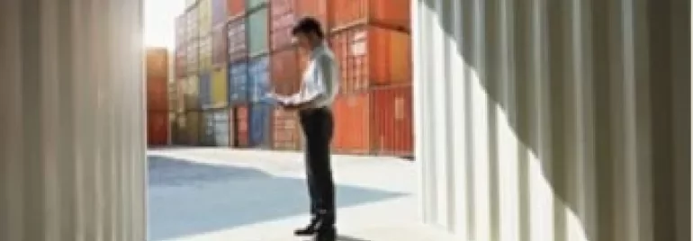 Homem de pé em um contêiner, verificando documentos.