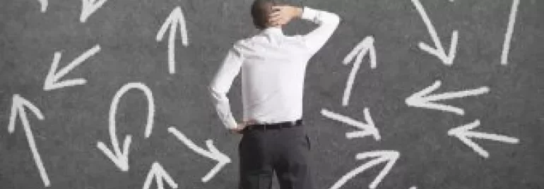 Homem confuso em frente a quadro cinza com flechas em várias direções.