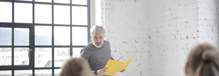 Homem apresentando papel amarelo em escritório moderno.