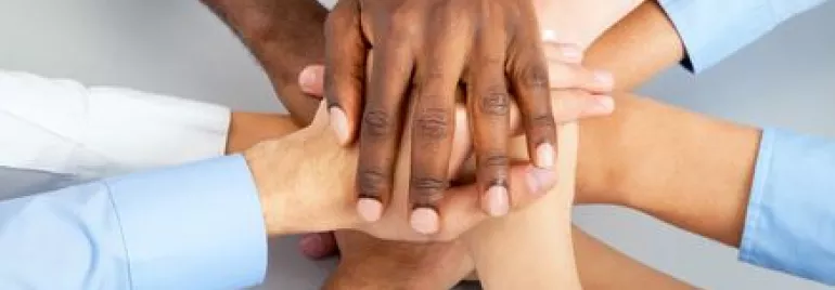 Mãos de várias pessoas unidas em sinal de colaboração.