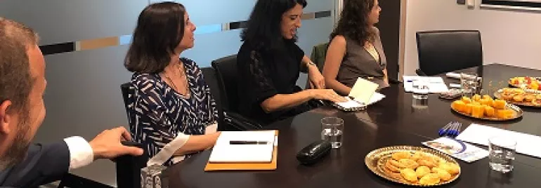 Reunião em sala de conferência com quatro pessoas e lanches na mesa.