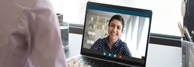 Mulher em videochamada olhando para um laptop.