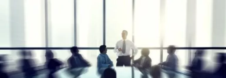 Reunião de negócios com pessoas ao redor de uma mesa em sala iluminada.