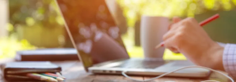 Pessoa trabalhando ao ar livre com laptop e smartphone.