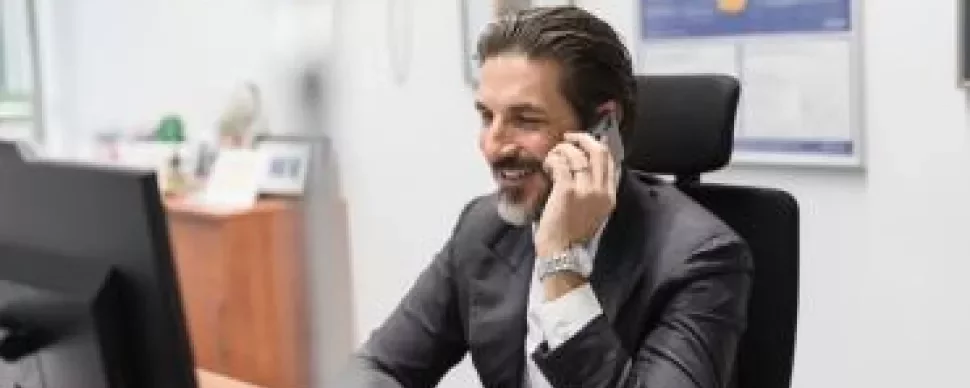Homem sorrindo ao telefone no escritório.