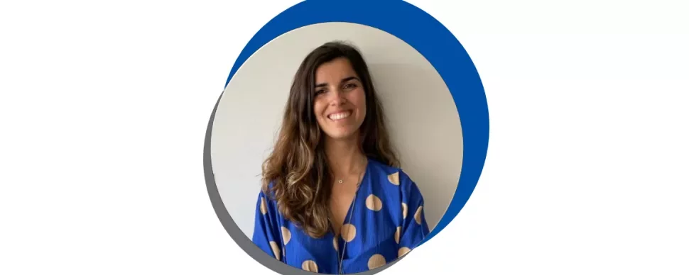 Mulher sorridente com blusa azul de bolinhas.