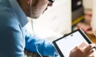 Homem usando um tablet com fones de ouvido.