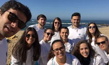 Grupo de pessoas sorrindo na praia em um dia ensolarado.