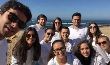 Grupo de pessoas sorrindo na praia em um dia ensolarado.