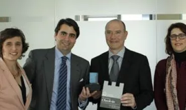 Grupo de pessoas sorrindo com troféu em escritório.