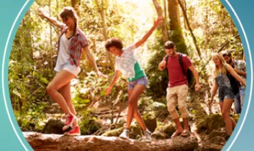 Grupo de jovens caminhando em floresta, equilibrando-se em tronco.