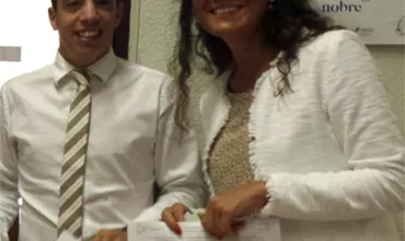 Duas pessoas sorrindo segurando papéis em um escritório.