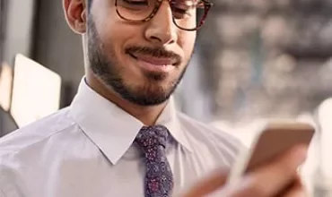 Homem com camisa e gravata olhando para o celular.