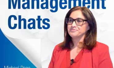 Mulher de óculos em palestra 'Management Chats'.