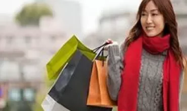 Mulher segurando sacolas de compras e sorrindo.