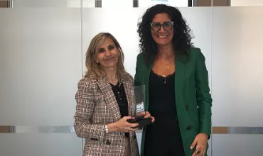 Duas mulheres posam com troféu em um escritório.