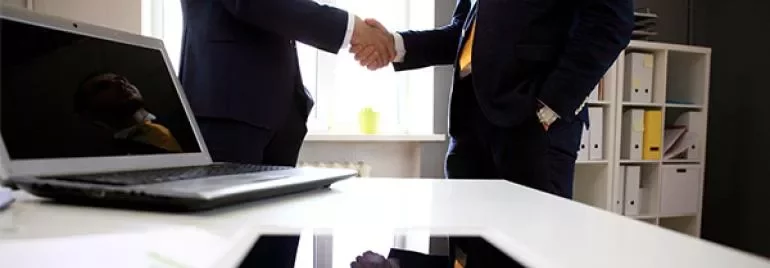 Dois homens de negócios apertando as mãos em um escritório.