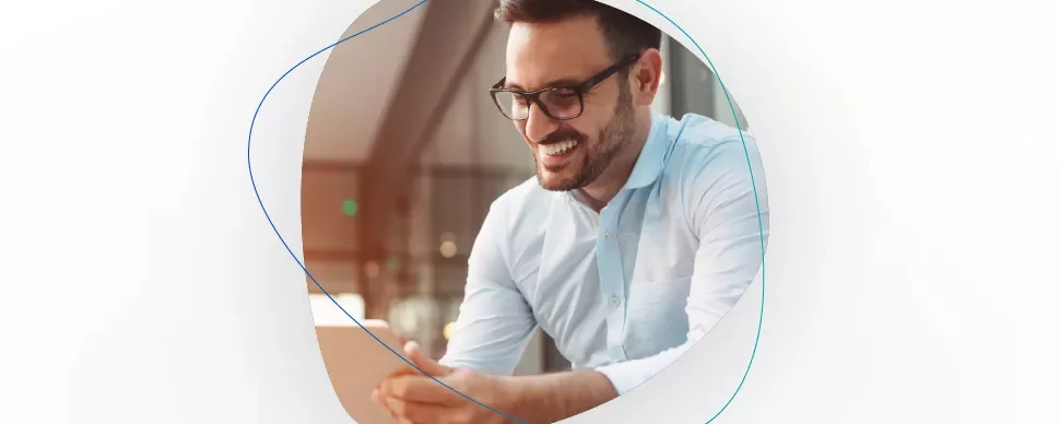 Homem sorridente com óculos e camisa azul clara, segurando um tablet.
