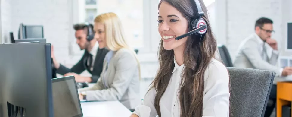 Funcionários em um escritório usando headset para atendimento.