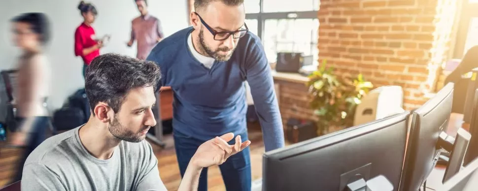 Dois homens trabalhando em frente ao computador.