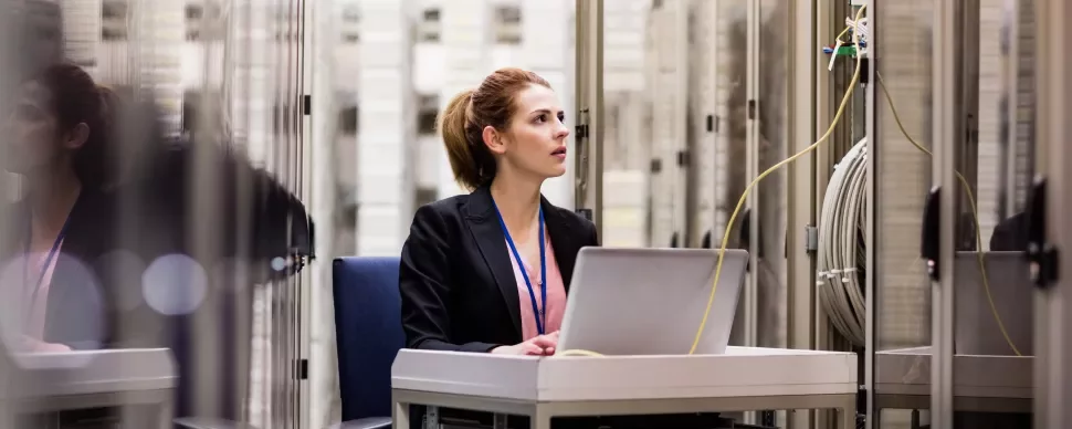 Mulher trabalhando em um data center com laptop.