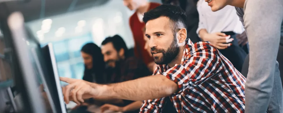 Grupo de pessoas em um escritório colaborando em um projeto no computador.