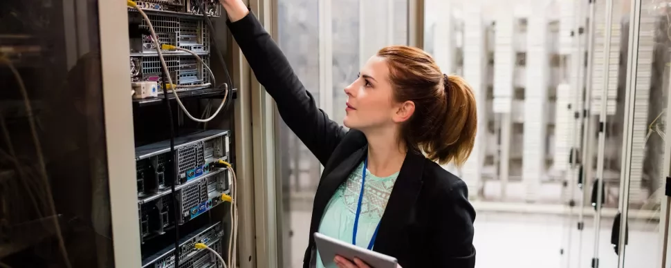 Técnica em data center ajustando servidores.