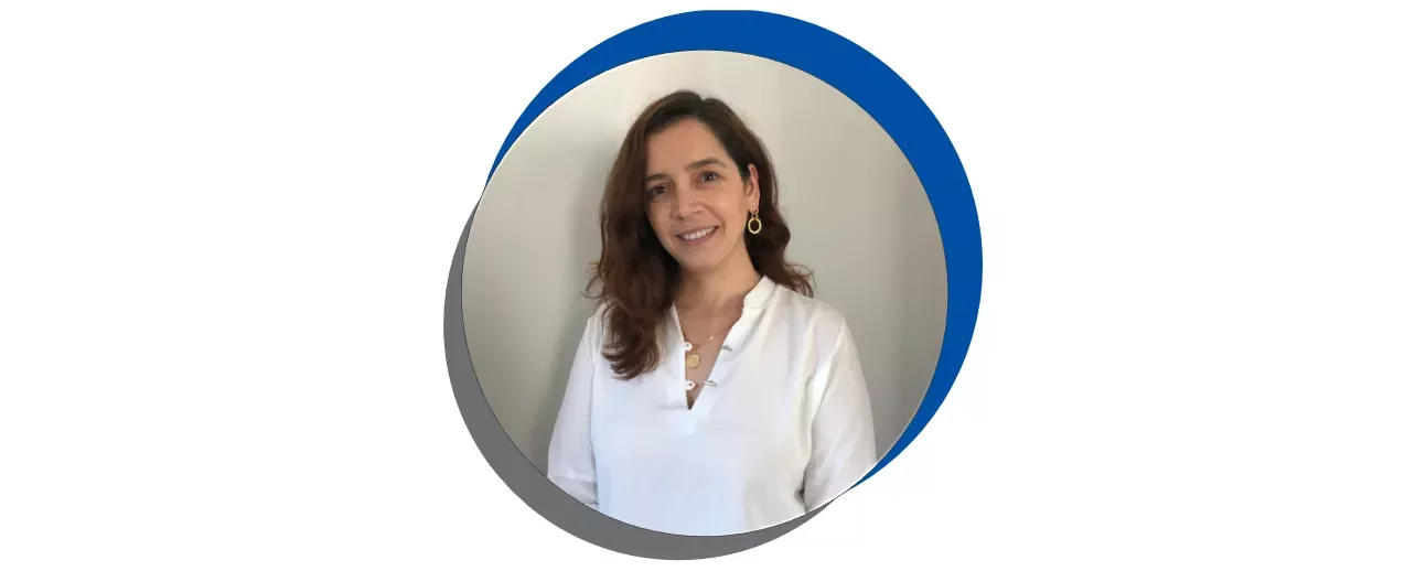 Mulher sorrindo de camisa branca em fundo azul e cinza.