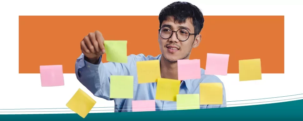 Homem organizando post-its coloridos em um quadro transparente.