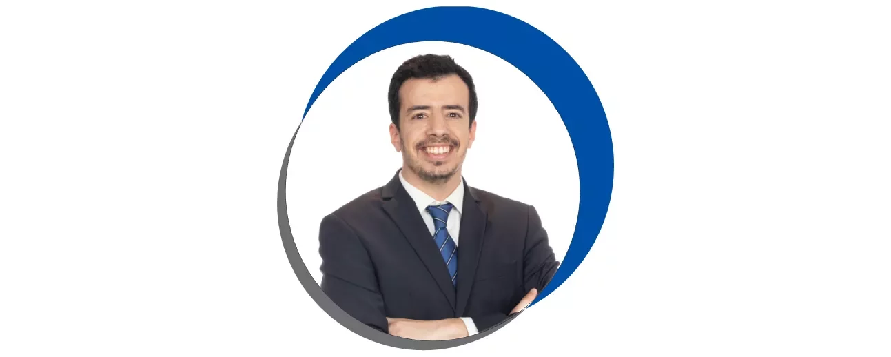 Homem sorridente em terno, fundo branco, circulo azul e cinza.