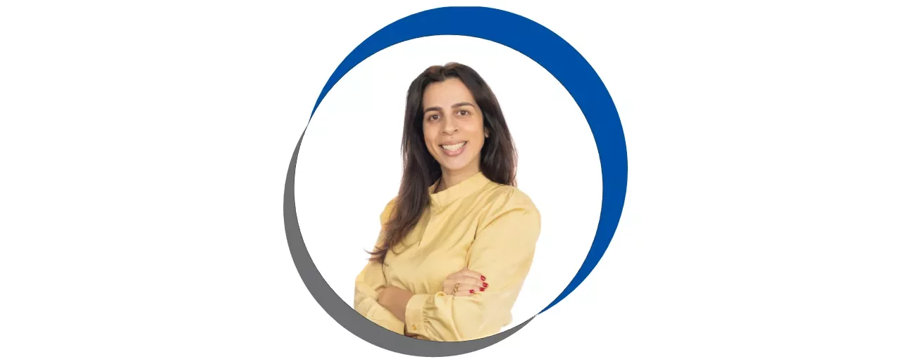Mulher sorridente com blusa amarela, braços cruzados.