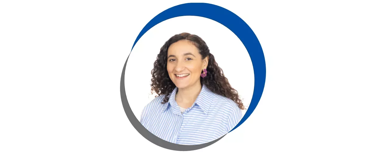 Mulher sorridente com cabelo cacheado em uma moldura circular azul e cinza.