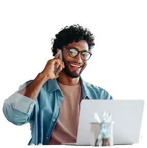 Um homem em um escritório, segurando um laptop enquanto faz uma ligação.