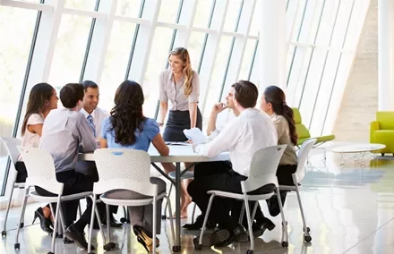 Equipe discutindo em reunião ao redor de mesa em escritório moderno.