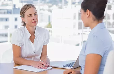 Duas mulheres conversando em uma mesa de escritório.